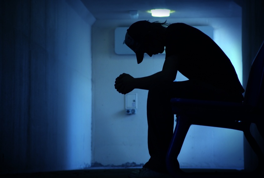 silhouette of man sitting on a bench in a depressed state
